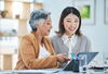 A mature woman talking to a younger woman while they both look at a computer screen